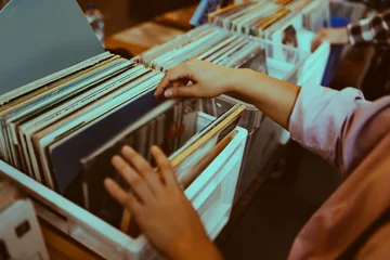 Fotobehang Muziekwinkel Vrouw kiest een vinylplaat in een muziekwinkel