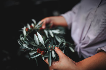 Woman is holding in the hands the wreath of flowers. Beautiful nature floral head crown. Trendy...