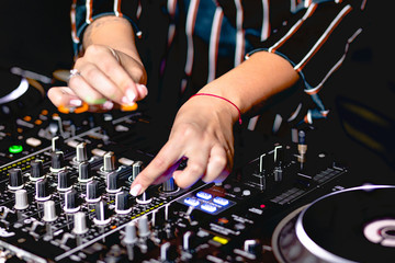 Young girl female shot party dj audio controlling mixing. Turntable High quality Sound mixing controller disc jockey hands of woman in night club party, Pro audio equipment on stage in nightclub . 