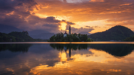 Naklejka premium Lake Bled Slovenia. Beautiful sunrise over Bled lake with small Pilgrimage Church. Most famous Slovenian lake and island Bled with Pilgrimage Church of the Assumption of Maria. Bled, Slovenia.