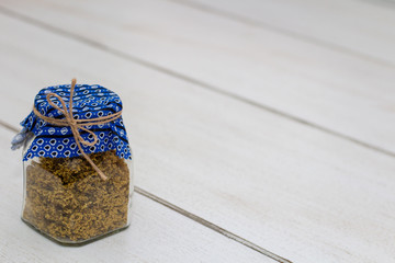 Dried elderberry flowers in a vintage glass jar on a white wooden table