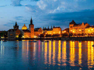 Fototapeta na wymiar Historical buildings of Smetana Embankment reflected in the water of Vltava River on summer evening. Prague, Czech Republic.