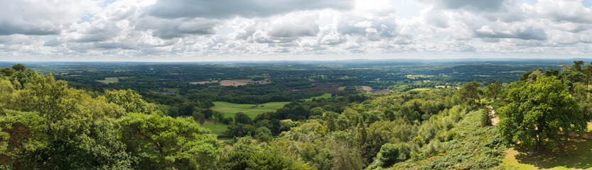Fototapeta na wymiar Panoramic view of the Surrey and Sussex countryside from the North Downs to the South Downs in England, UK. Taken from the top of Leith Hill Tower on a cloudy summer's day.