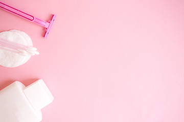 top view personal care products. white bottle, razor, ear sticks, cotton pads, toothbrush on pink background. copy space