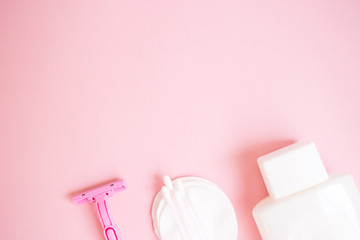 top view personal care products. white bottle, razor, ear sticks, cotton pads, toothbrush on pink background. copy space