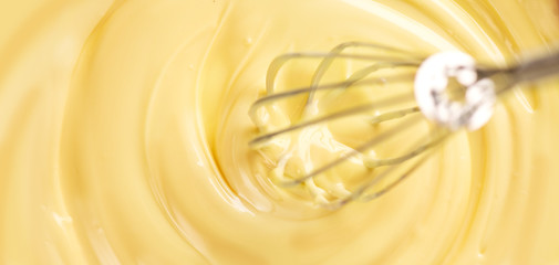 White chocolate. Melted liquid white chocolate mixing with a wisk. Closeup of molten liquid hot...