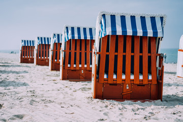 Blue striped roofed wooden chairs stands in line on sandy beach on sunny day. Travemunde, Luebeck, Germany