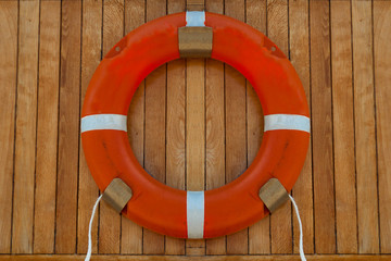 Orange color life buoy on wood panel