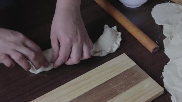 manos de mujer armando empanada rellena con carne