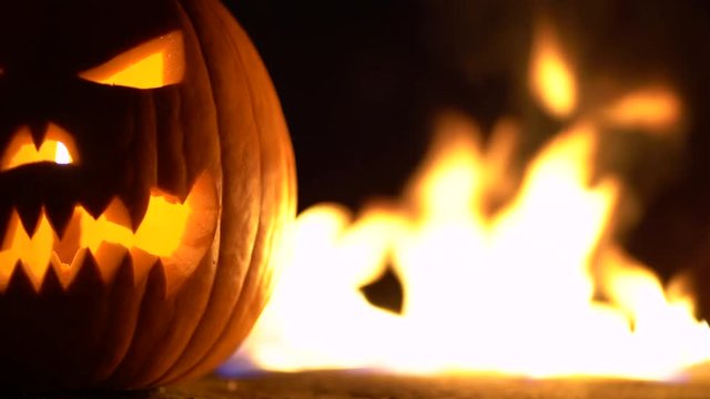 Terrible pumpkin as head of jack-o-lantern with carved eyes and wicked smirk in burning hell fire flames. Scary symbol of Halloween holidays art design, celebration. 4k