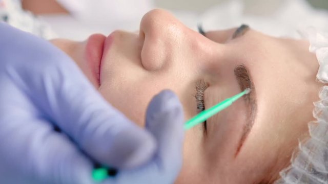 Cosmetologist making degrease eyebrows or applying primer using microbrush