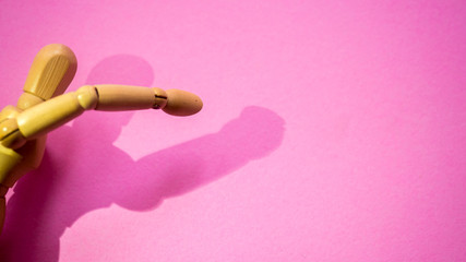 Wooden dummy  and shadow on pink background