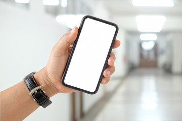 Man's hand shows mobile smartphone with white screen over blurred background.