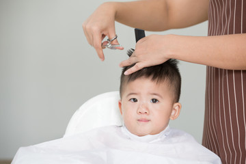 Baby boy cutting hair by his mom at home