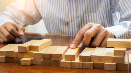 Business man hand put wooden blocks arranging stacking for development as step stair, Concept of growth and success plan.