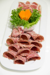 Salami sausage slice and vegetables on plate