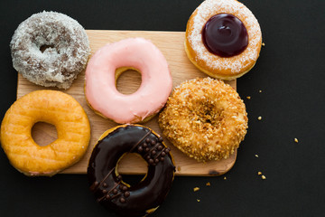 donuts on wood plate and black background.