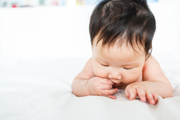 Asian baby girl with hand in mouth