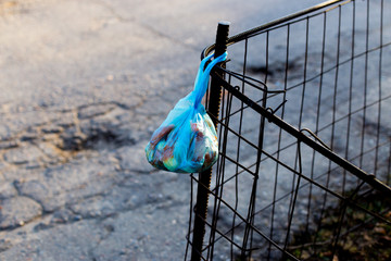 trash in a bag hanging on a fence