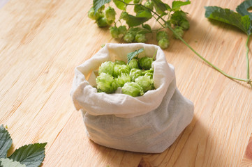 Fresh cones of hops in bag on  wooden background, Ingredient in beer industry. Craft beer brewing....