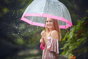 Happy beautiful girl with an umbrella in the rain during a fores