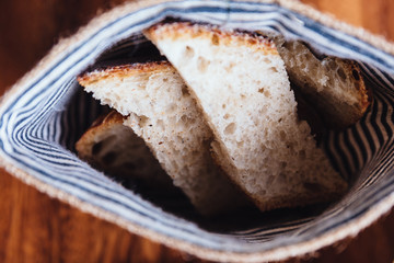 Fresh baked bread sliced for eating with Brie cheese in fabric pouch.
