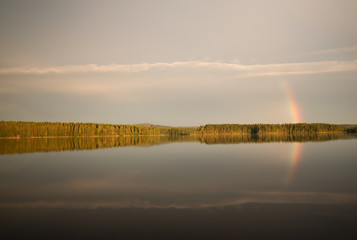 Calm lake in sweden with rainbow reflecting on the surface