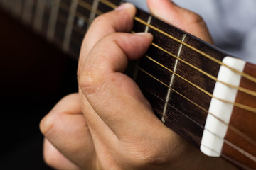 Musician's fingers on the strings of a guitar closeup