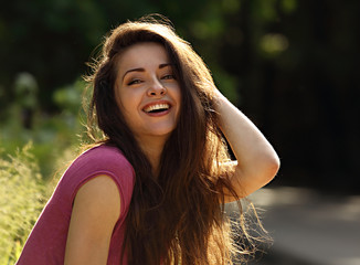 Fototapeta premium Beautiful toothy laughing enjoying young woman looking with long bright hair on nature bright sunny summer background. Closeup portrait