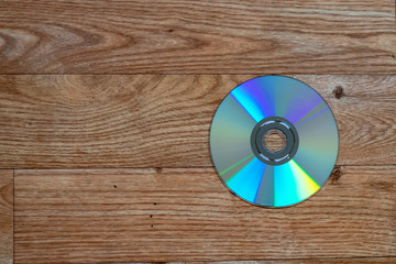 Single DVD disk lying on a wooden table with space beside