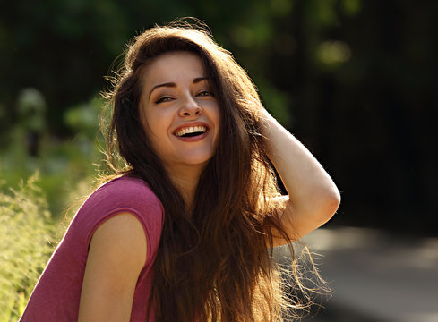 Beautiful toothy laughing enjoying young woman looking with long bright hair on nature bright sunny summer background. Closeup portrait