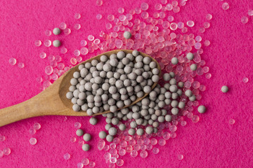 Pile of silica gel on spoon whih pink background, Desiccant used in industrial. moisture protection