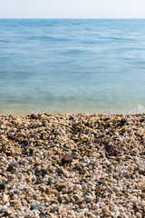 Waves of the blue sea quietly crashing onto a pebble beach in Maronia, Rodopi, Greece