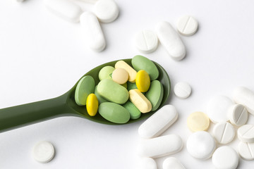 Assorted pharmaceutical medicine pills, tablets and capsules on plastic spoon