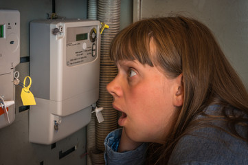 Woman is checking electricity meter - expensive electricity conc