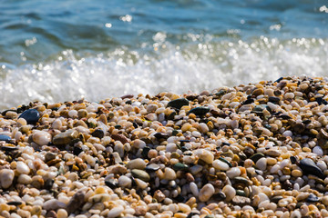 Waves of the blue sea crashing onto a pebble beach in Maronia, Rodopi, Greece