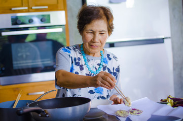 lifestyle portrait of senior happy and sweet Asian Japanese retired, woman cooking at home kitchen...