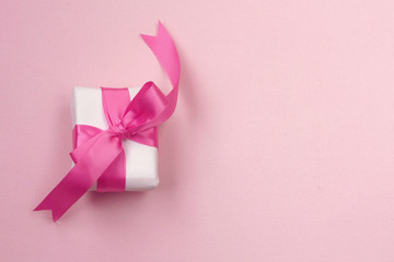 wrapped gift box with pink bow, on paper texture background