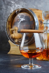 Strong alcoholic drink cognac in sniffer glass with smoking cigar, crystal decanter and vintage...