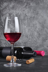 Red wine bottles with glass for tasting and corkscrew in cellar