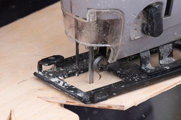 jigsaw electric gray in the work, sawing plywood complex shape according