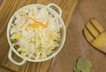 Sauerkraut in a bowl on a wooden background.