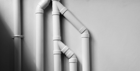 white plastic pipe at white cement wall with shadow.