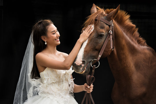 portrait of a beautiful young asian woman bride and brown horse