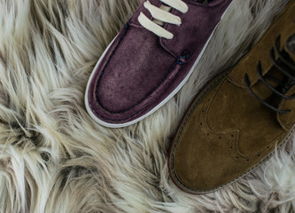 Two pairs of suede shoes: male and female on fur background.