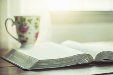 open bible  book with a cup of coffee against window light in the morning, christian devotional
