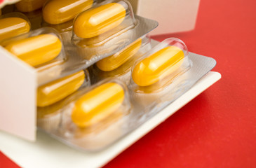 Yellow pills in a blister on a red background.