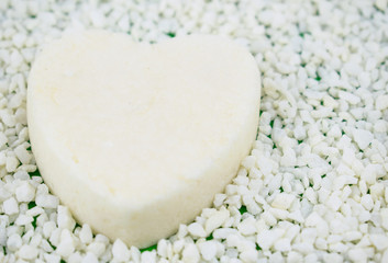 White heart from soap and   on a light background of small stones.