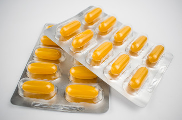 Yellow pills in a blister on a white background.