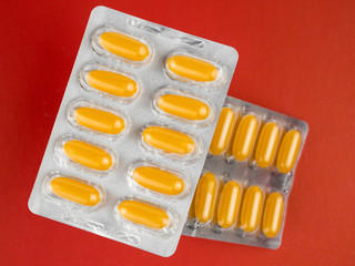 Yellow pills in a blister on a red background.